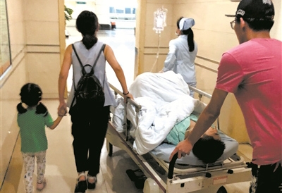6月20日，王慧左手牵着女儿，右手扶着病床，送郑培进前往手术室抢救
