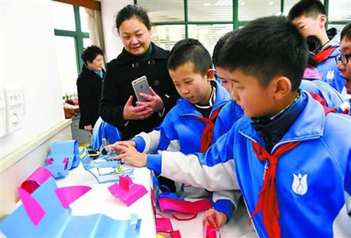 美术课上，静教院附校的同学们正在分享各自设计制作完成的“纸椅子”。　