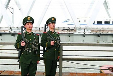 战士们在执勤，身后一列列车疾驰而过