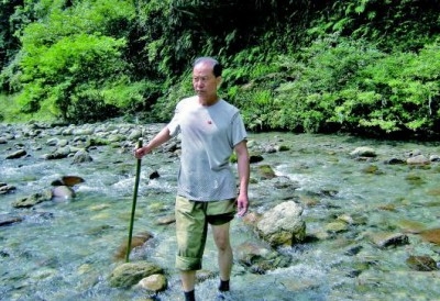 退伍老兵王新法在湖南石门县薛家村的河道里探测,准备为村里修桥